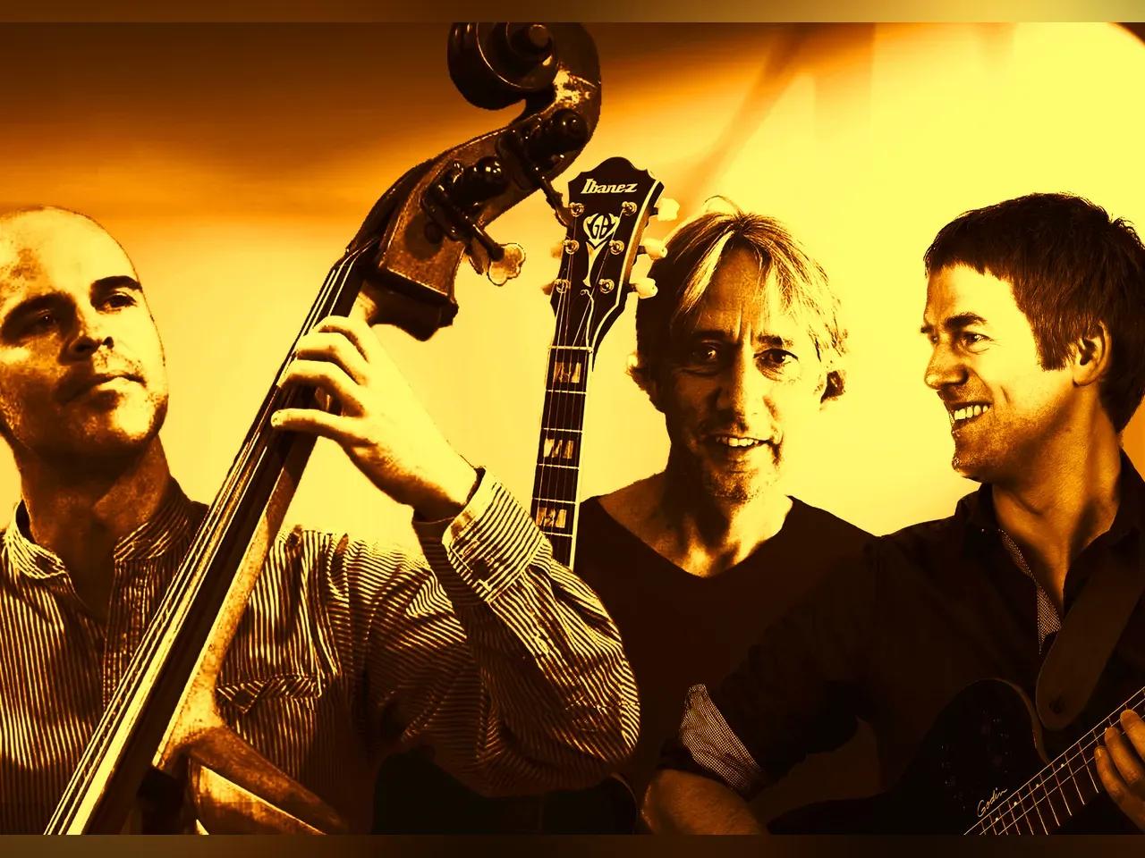 Gelblich eingefärbtes Foto mit drei Musikern mit Kontrabass und Gitarre.