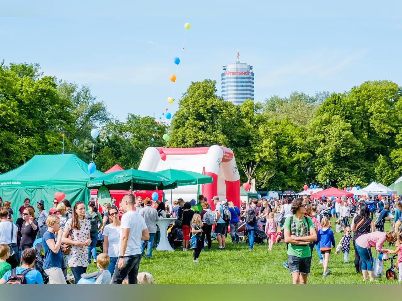 Partner-Stände und viele Gäste stehen zum Dein Tag im Paradies auf einer Rasenfläche im Park