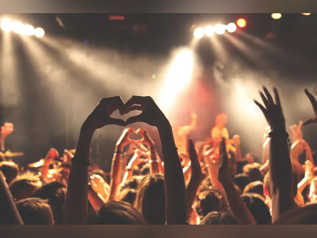 Konzertpublikum mit erhobenen Armen und Hände, die ein Herz formen 