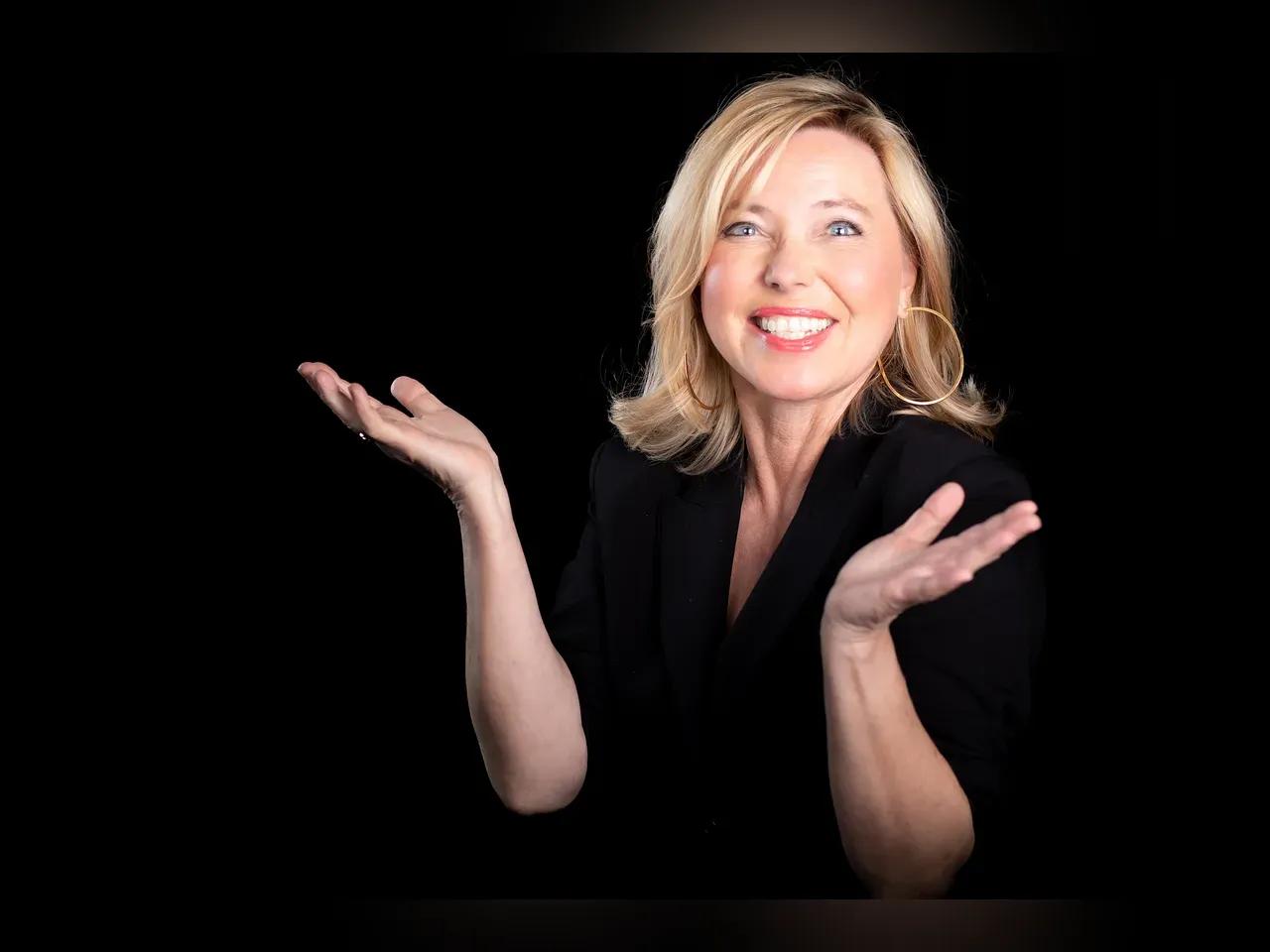 Simone Solga lächelnd die Hände hebend vor schwarzem Hintergrund