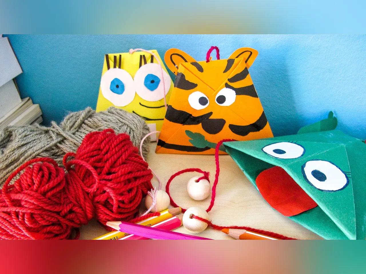 Bunter Basteltisch mit Schnüren, Stiften und lustigen Tierköpfen aus Papier.
